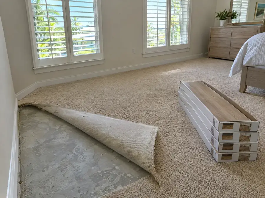Bedroom carpet pulled back to the slab with boxes of vinyl plank ready